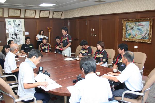 丸テーブルに「SRS ブラックビーンズ」の選手、市長、関係者の方々が座り、1名の選手が立って話をしている写真